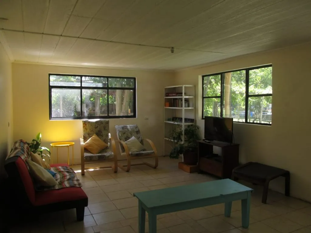Sala de estar del hostal Río Laja con sillones, TV y ventanas con vista al jardín